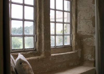 Banc en pierre et fenêtres anciennes dans une chambre d'hôtes du sud de la France